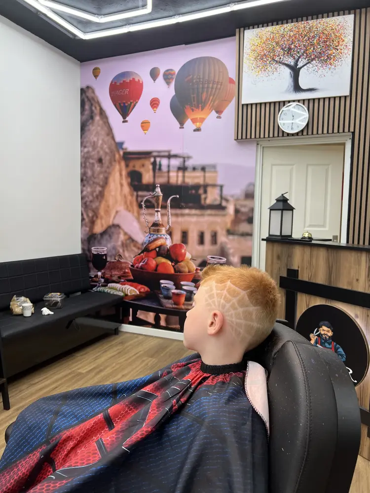 A boy in the barber chair in front of the Cappadocia hot air balloon mural
